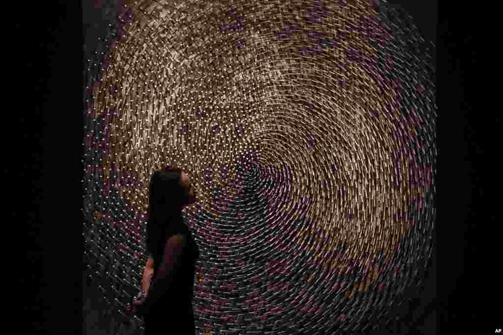 A Christie&#39;s auction house employee poses for photographs next to one part of German Sculptor&#39;s Guenther Uecker&#39;s &quot;Spirale I, Spirale II (Doppelspirale)&quot; in London. The piece is estimated to fetch 1 to 1.5 million pounds ($1.2 to $1.8 million, 1.1 to 1.7 million euro) in an evening auction on March 7.