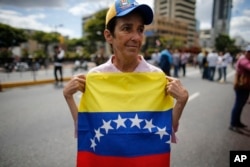 A woman holds a Venezuelan national flag as she takes part in a walk out against President Nicolas Maduro, in Caracas, Venezuela, Jan. 30, 2019.