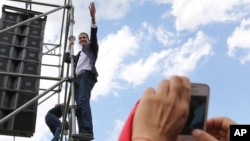 Venezuelan Congress President Juan Guaido waves from the scaffolding after speaking at a rally demanding the resignation of President Nicolas Maduro in Caracas, March 4, 2019.