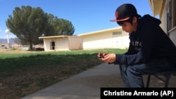 In this April 30, 2015 photo, Brian Olivas, 17, looks at his smartphone between classes at the Cuyama Valley High School in New Cuyama, California. The Cuyama Joint Unified School District is 60 miles from the nearest city.