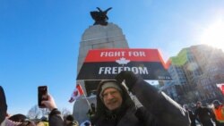 A man poses for a photo in front of the National War Memorial as truckers and supporters take part in a convoy to protest COVID-19 vaccine mandates for cross-border truck drivers in Ottawa, Ontario, Canada, Jan. 29, 2022.