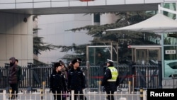 FILE - Policemen stand guard in front of the court building in Beijing.