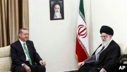 Supreme Leader Ayatollah Ali Khamenei (R) and Turkish Prime Minister Recep Tayyip Erdogan talk during their meeting in Tehran, Iran, Jan. 29, 2014. A portrait of the late Iranian revolutionary founder Ayatollah Khomeini hangs on the wall.