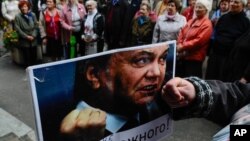 Eine Teilnehmerin einer Demonstration gegen Wahlbetrug haelt am Mittwoch (26.09.12) in Kiew, Ukraine, ein Bild des ukrainischen Praesidenten Wiktor Janukowitsch mit der Unterschrift "Ich werde mir jedermanns Forderungen anhoeren!"