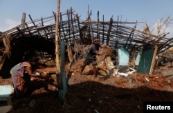 FILE - A fisherman and his wife clear the debris from their damaged house after Cyclone Phailin hit Gopalpur village in Ganjam district in the eastern Indian state of Odisha, Oct. 14, 2013.