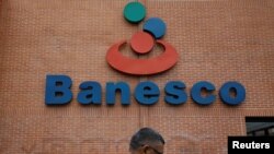 A man walks past the corporate logo of Banesco bank at one of its branches in Caracas, Venezuela, May 3, 2018. 