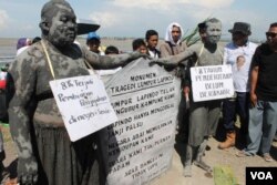 Tugu peringatan dan dua orang manusia lumpur menuntut keadilan dalam peringatan 8 tahun musibah lumpur Lapindo, Kamis, 29 Mei 2014 (Foto: VOA/Petrus Riski)