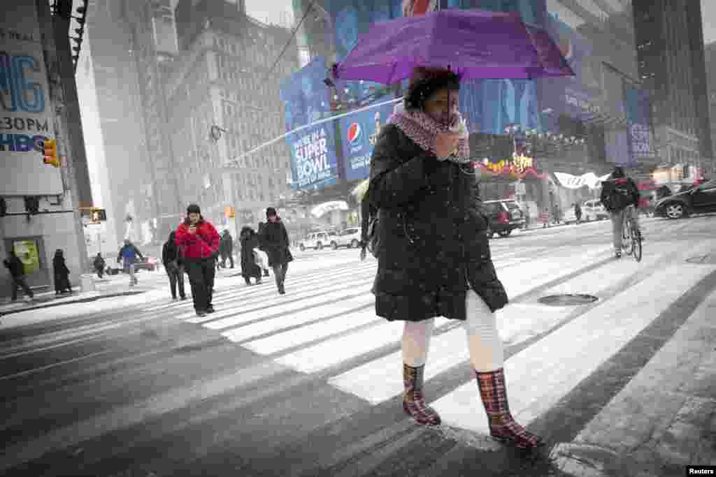ایک خاتون چھتری اٹھائے سڑک پار کر رہی ہے۔