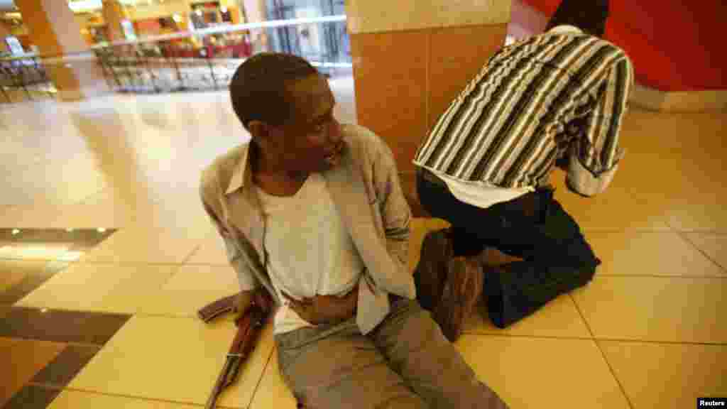 An injured policeman holds on to his wound as his compatriot searches through the Westgate Shopping Mall for gunmen in Nairobi, September 21, 2013.