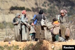 Internally displaced people, covered with mud, wait as they are stuck in the town of Khirbet al-Joz, in Latakia countryside, waiting to get permission to cross into Turkey near the Syrian-Turkish border, Syria, Feb. 7, 2016.