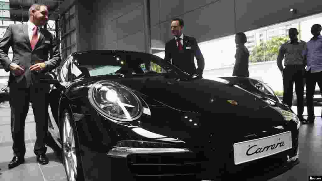 Company representatives stand beside a vehicle by German car maker Porsche in Lagos, Nigeria.