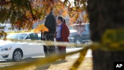 Yia Lee watches police investigate her neighbor's house in Fresno, California, Monday, Nov. 18, 2019. (AP Photo/Gary Kazanjian)