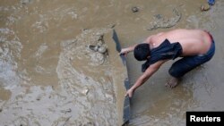Một người dân thủ đô Manila đang dọn bùn đất khỏi một con đường sau khi bão tràn vào.
