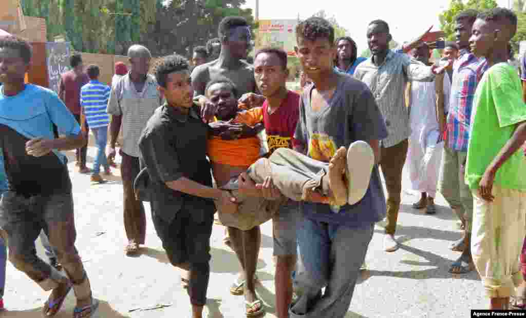 People carry a man injured during protests against a military coup in Sudan that overthrew the transition to civilian rule, in the capital Khartoum,&nbsp; Oct. 25, 2021.