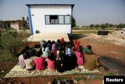 Children watch as volunteer teachers perform a puppet show inside a mobile educational caravan for children who do not have access to schools on the outskirts of the Syrian rebel-held town of Saraqib, Idlib province, March 10, 2016.