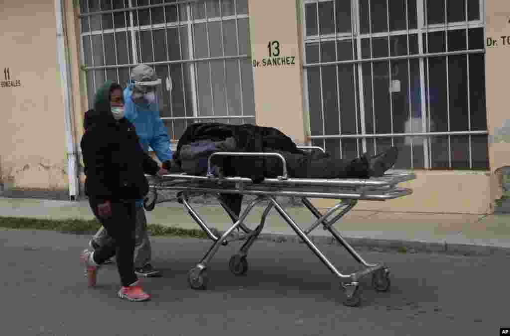 A healthcare worker dressed in protective gear pushes the body of a man, who died of COVID-19, on a stretcher outside the General Hospital in La Paz, Bolivia.