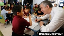 Education Secretary Arne Duncan visits with young student Mario Corona, age 6, in kindergarten at McGlone Elementary School in the Montbello section of Denver, in this May 14, 2015.