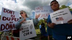 FILE - Protesters holds signs as they stand with others outside an event where Republican presidential candidate, Donald Trump and New Jersey Gov. Chris Christie were to appear on May 19, 2016 in Lawrenceville, N.J. 