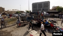 Men walk past the site of a suicide bomb attack in Baghdad, Iraq, Sept. 17, 2015. 