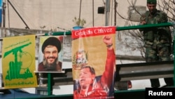 FILE - A Lebanese soldier stands beside posters of Hezbollah leader Sayyed Hassan Nasrallah and Venezuela's President Hugo Chavez on a bridge in Beirut, Dec. 1, 2006. 