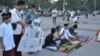 A family lays out a newspaper to be seated for morning prayer. (K. Varagur/VOA)