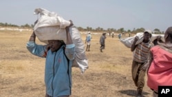 Des sud-soudanais transportent des rations alimentaires dans l'État de Leer, au Soudan du sud, le 6 mars 2017.