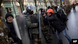 A photographer takes photos of an opposition supporter during a march toward parliament in Kyiv, Feb. 6, 2014.