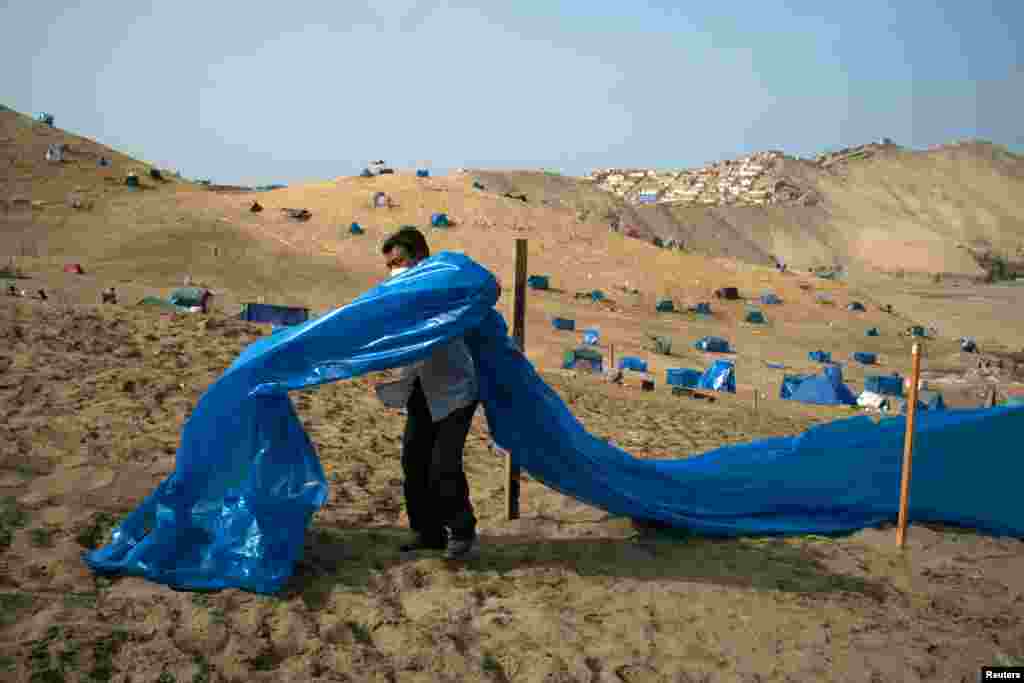 A man marks a plot of land on the Morro Solar as people are occupying the area amidst the outbreak of the COVID-19, in Chorrillos, Peru, April 10, 2021.