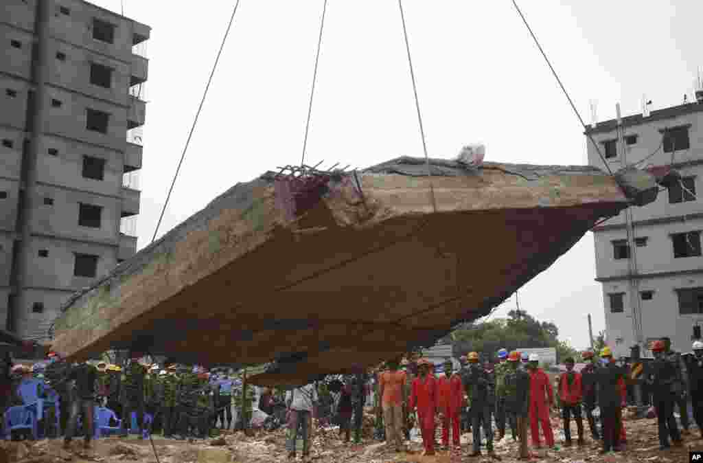 Workers watch as a crane lowers the ceiling of the garment factory building which collapsed in Savar, near Dhaka, Bangladesh, April 29, 2013.