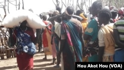 A South Sudanese woman walks away with a large bag of maize that she received in exchange for working in a drought-hit area of Northern Bahr el Ghazal. The project, called "Food for Assets", is run by international NGO, Mercy Corps.