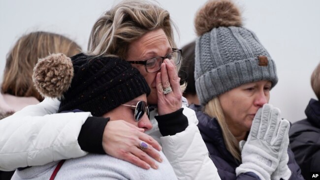 Mourners grieve at a memorial at Oxford High School in Oxford, Mich., Wednesday, Dec. 1, 2021. Authorities say a 15-year-old sophomore opened fire at Oxford High School, killing four students and wounding seven other people on Tuesday. (AP Photo/Paul Sancya)