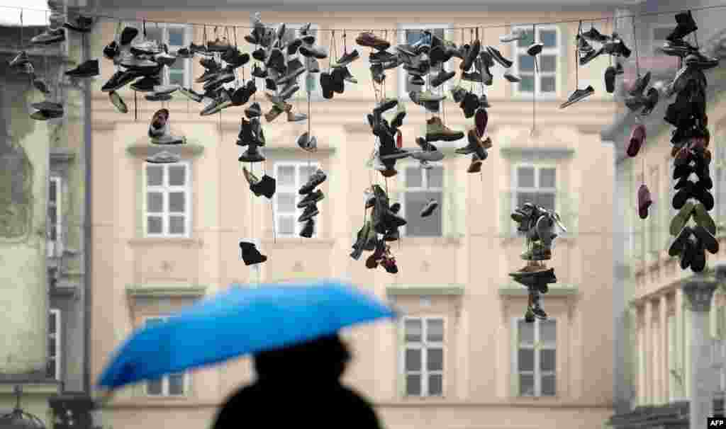 A woman walks underneath shoes hanging from a power line in the center of the Slovenian capital Ljubljana.