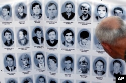 FILE - A man looks at a banner with pictures of Serbs killed by Bosnian forces during the 1992-95 Bosnian war in the Srebrenica area, in downtown Belgrade, Serbia, July 10, 2017.