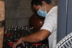 An employee wearing a face mask is busy bottling the company's rum, Phnom Penh, March 31, 2020. (Phorn Bopha /VOA Khmer)