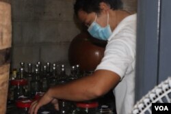 An employee wearing a face mask is busy bottling the company's rum, Phnom Penh, March 31, 2020. (Phorn Bopha /VOA Khmer)