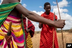 In this photograph taken Tuesday July 2, 2019, Saitoti Petro, right, speaks to young herdsmen near the village of Loibor Siret, Tanzania.