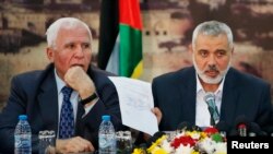 The head of the Hamas government Ismail Haniyeh shows a signed reconciliation agreement as he attends a news conference with Senior Fatah official Azzam Al-Ahmed (L) in Gaza City, Apr. 23, 2014.
