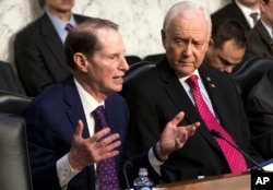 Sen. Ron Wyden, D-Ore., left, the top Democrat on the Senate Finance Committee, criticizes the Republican tax reform plan while Chairman Orrin Hatch, R-Utah, listens to his opening statement as the panel begins work overhauling the nation's tax code.