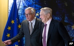 FILE - EU commission President Jean-Claude Juncker, left, welcomes George Soros, Founder and Chairman of the Open Society Foundation, prior to a meeting at EU headquarters in Brussels on Thursday, April 27, 2017.