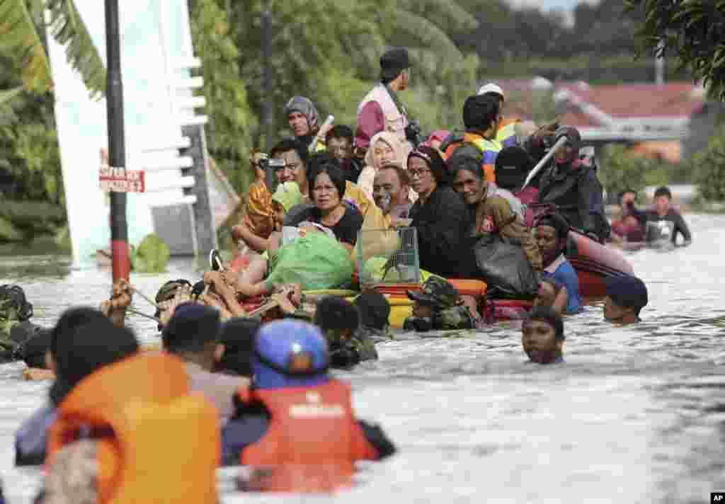 Residents evacuate their flooded homes in Makassar, South Sulawesi, Indonesia. Torrential rains and landslides displaced upwards of several thousand residents in central Indonesia, officials said.