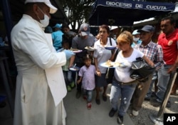 Priest Richard Garcia hands out free lunches to Venezuelan migrants at the "Divina Providencia" migrant shelter in La Parada, near Cucuta, on the border with Venezuela, Colombia, Monday, Feb. 11, 2019.