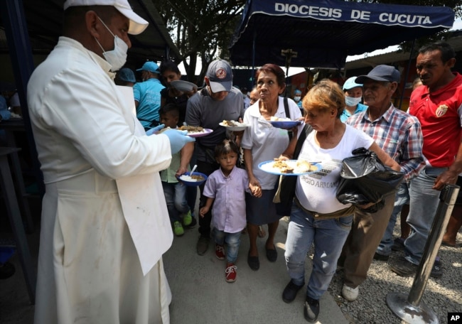Priest Richard Garcia hands out free lunches to Venezuelan migrants at the "Divina Providencia" migrant shelter in La Parada, near Cucuta, on the border with Venezuela, Colombia, Monday, Feb. 11, 2019.