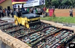 Police use a road roller to destroy bottles of illegal alcohol confiscated in Serpong, on the outskirts of Jakarta, Indonesia, April 13, 2018. Deaths from drinking toxic bootleg alcohol in Indonesia have exceeded 100 this month.