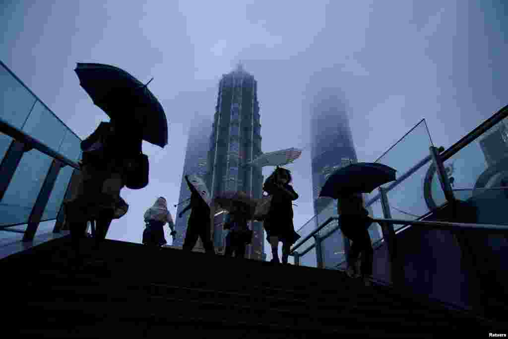 People hold umbrellas amid rainfall as Typhoon Chanthu approaches, in Shanghai, China.