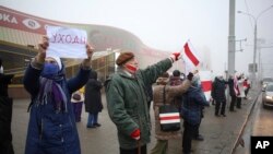 People with old Belarusian national flags and a poster reads "(Lukashenko) Go away" attend an opposition action to protest the official presidential election results in Minsk, Belarus, Monday, Jan. 4, 2021.