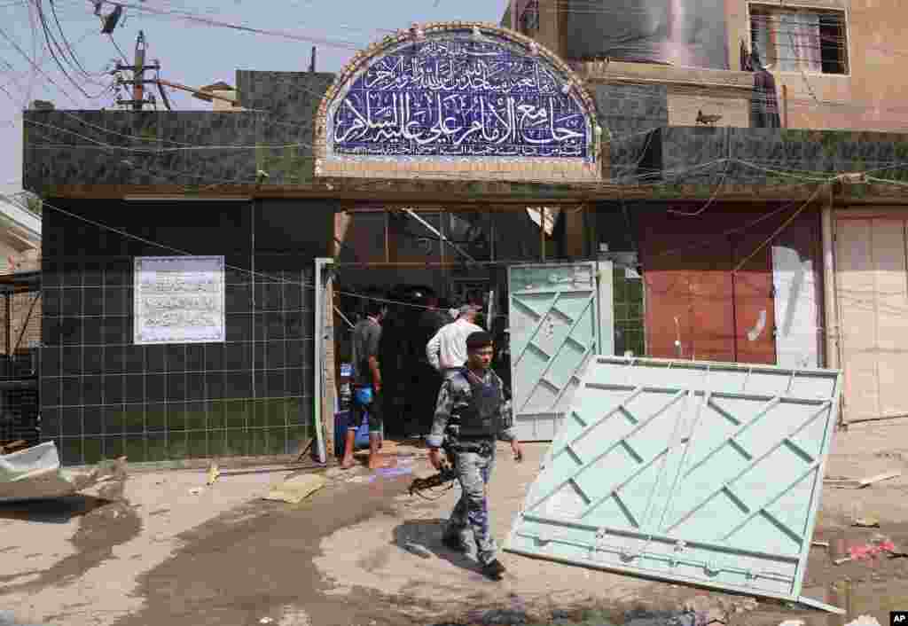 Security forces and civilians inspect the damage outside the Imam Ali mosque in New Baghdad, Aug. 25, 2014.