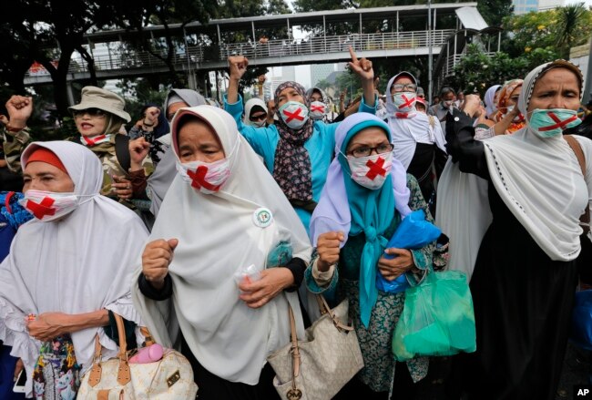 Para pendukung capres Prabowo Subanto mengenakan masker dalam unjuk rasa dekat gedung Mahkamah Konstitusi di Jakarta, Jumat, 14 Juni 2019. (Foto: AP)