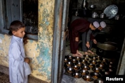 A boy stands while Pakistani religious students prepare food for their schoolmates at Darul Uloom Haqqania, an Islamic seminary and alma mater of several Taliban leaders, in Akora Khattak, Khyber Pakhtunkhwa province, Sept. 14, 2013.