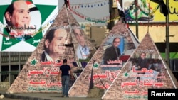 A man walks near replicas of Giza Pyramid covered with banners of presidential candidate and former army chief Abdel Fattah al-Sissi in Cairo, May 26, 2014.
