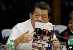 Kam Sin Wong, a Chinese junket operator in the Philippines, presents a photo as hearings into how about $81 million of Bangladesh's stolen funds were transmitted online to four private accounts at a branch of the Rizal Commercial Banking Corp. are held.